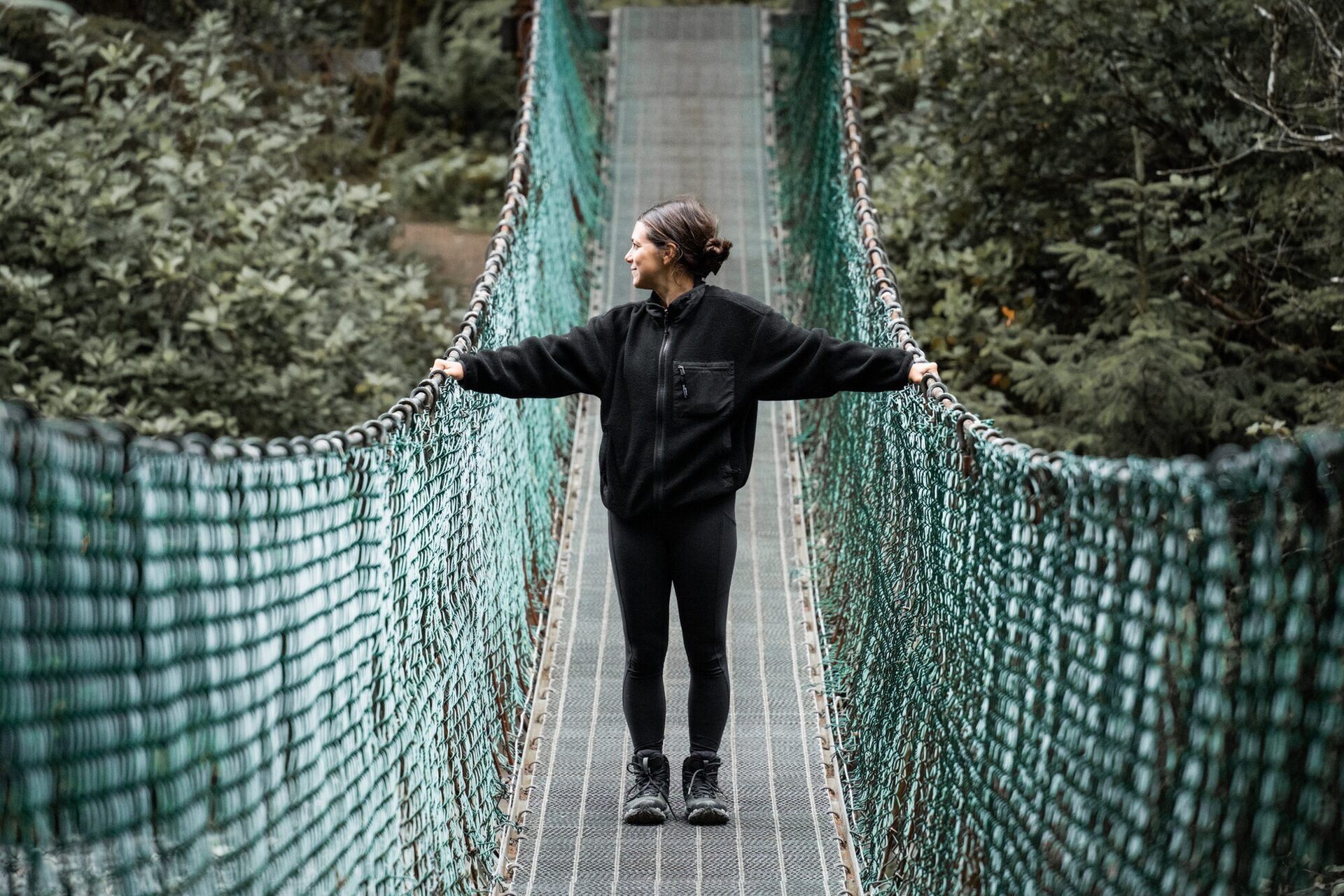 Andi Cross standing on a suspension bridge during a Canadian expedition